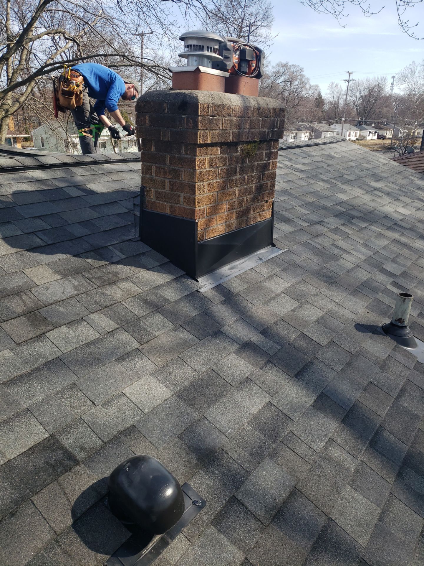 Above Roofing crew member installing new chimney flashing on a Wyoming, MI roof