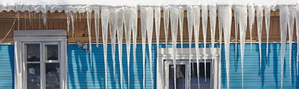 Icicles that have formed on the side of a house, causing ice dams