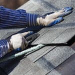 Roofing installer adding shingles to a roof