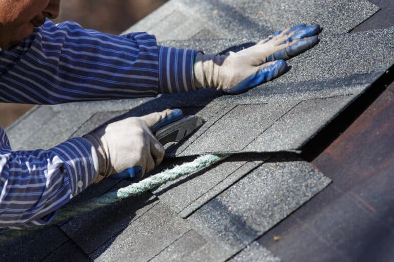Roofing installer adding shingles to a roof